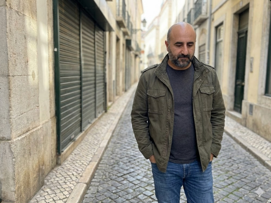 Man in casual jacket walking on a cobblestone street in Lisbon, modern urban scene